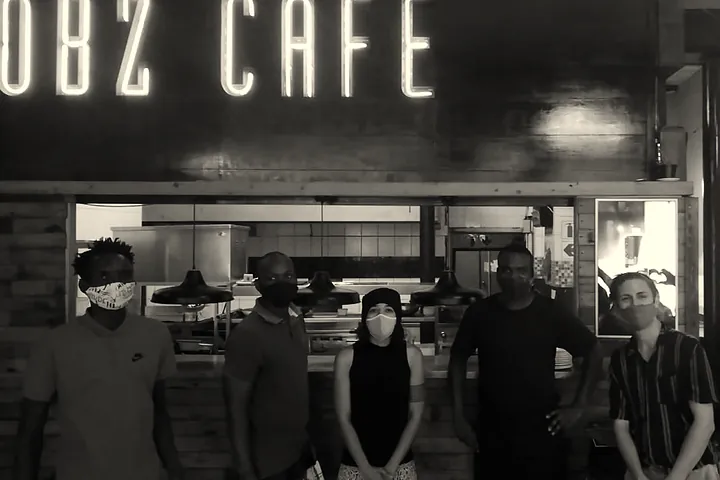 The Obz Café team under the old neon sign